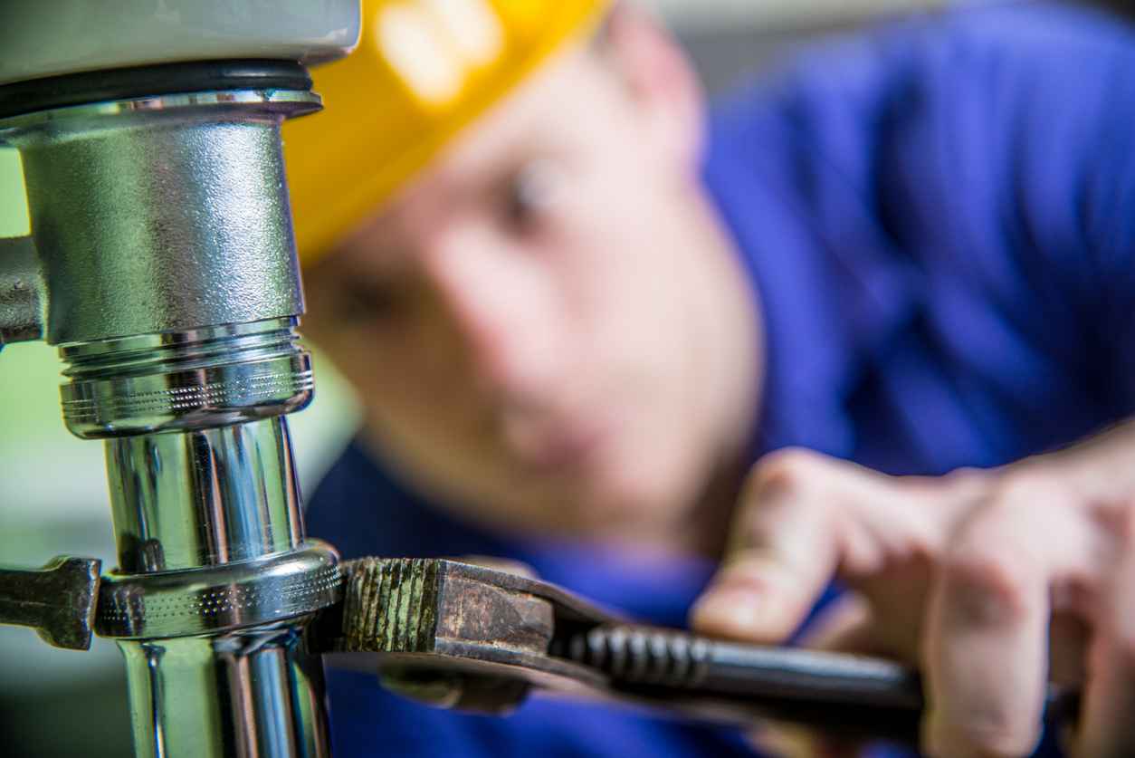 Plumber trying to unscrew a drain.