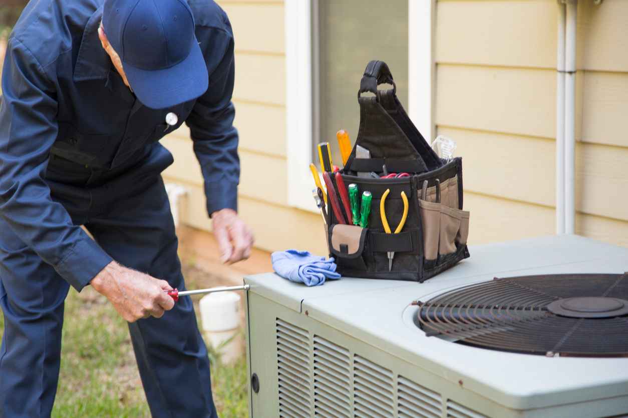 HVAC technician servicing an outside AC unit.