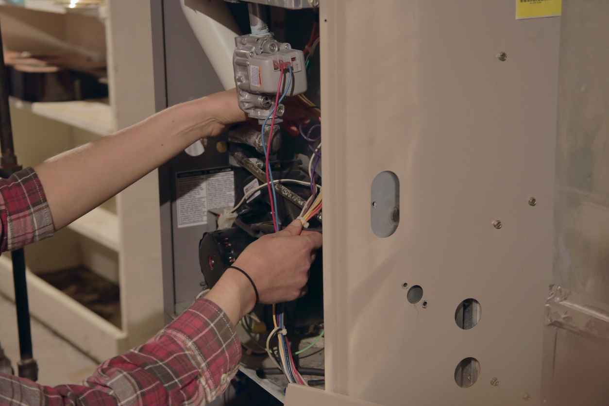 An HVAC technician working on a furnace unit system