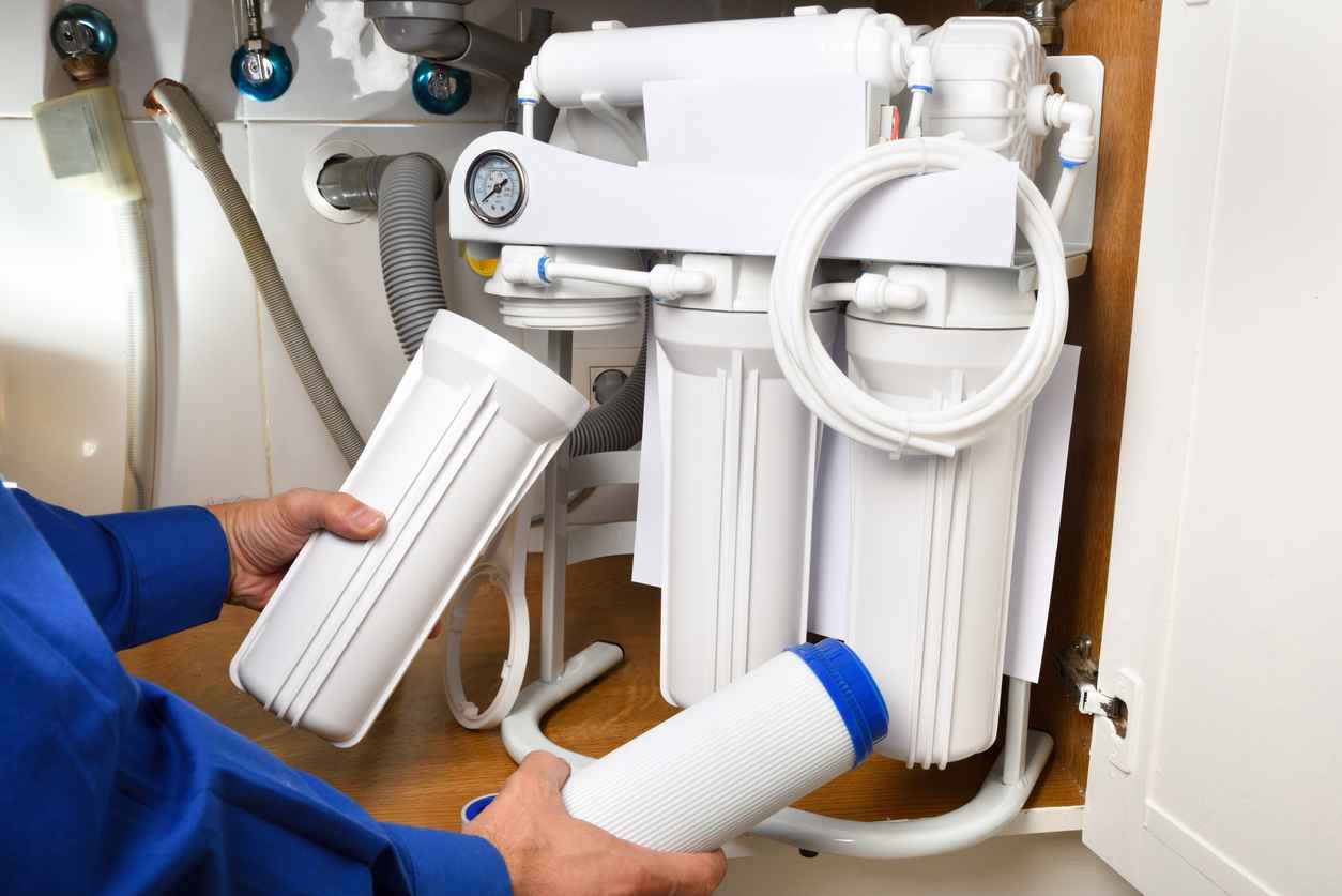 Technician installing reverse osmosis equipment under the sink