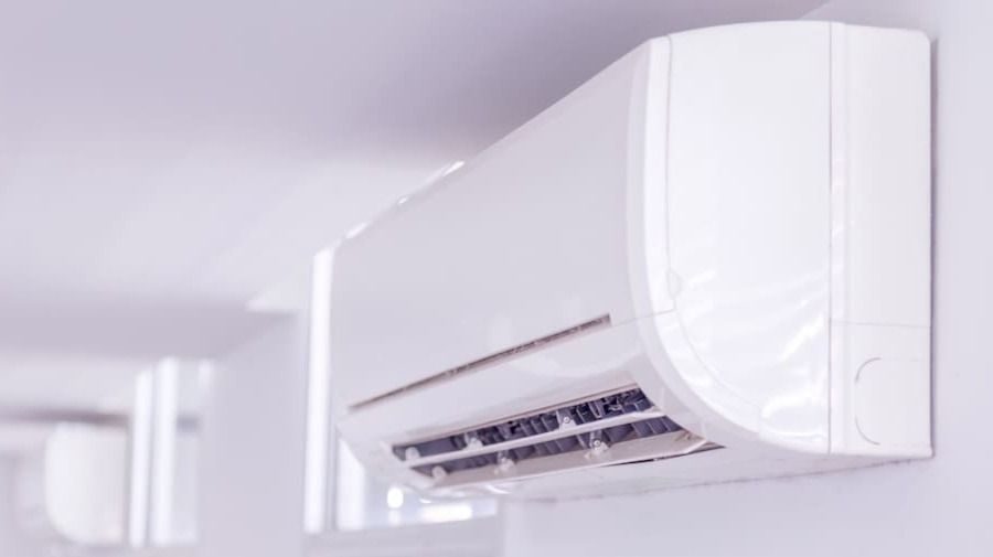 White wall-mounted air conditioner indoor unit with vents open in a bright room